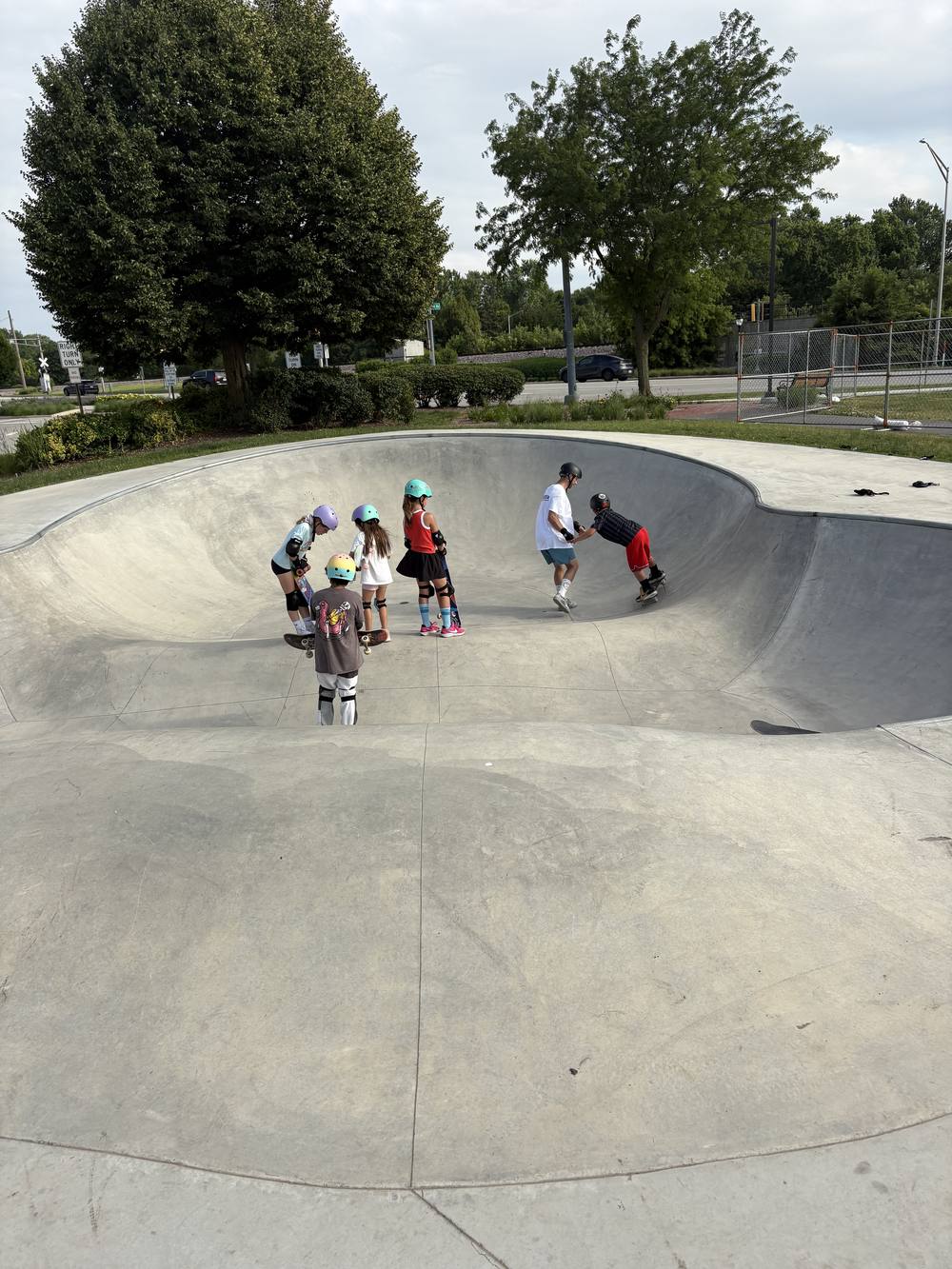 A coach helping two young skaters practice on a mini ramp at Recreation Park skate park in Arlington Heights
