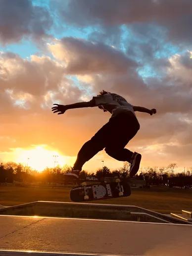 Coach Christopher Lagondino jumping his skateboard at sunset