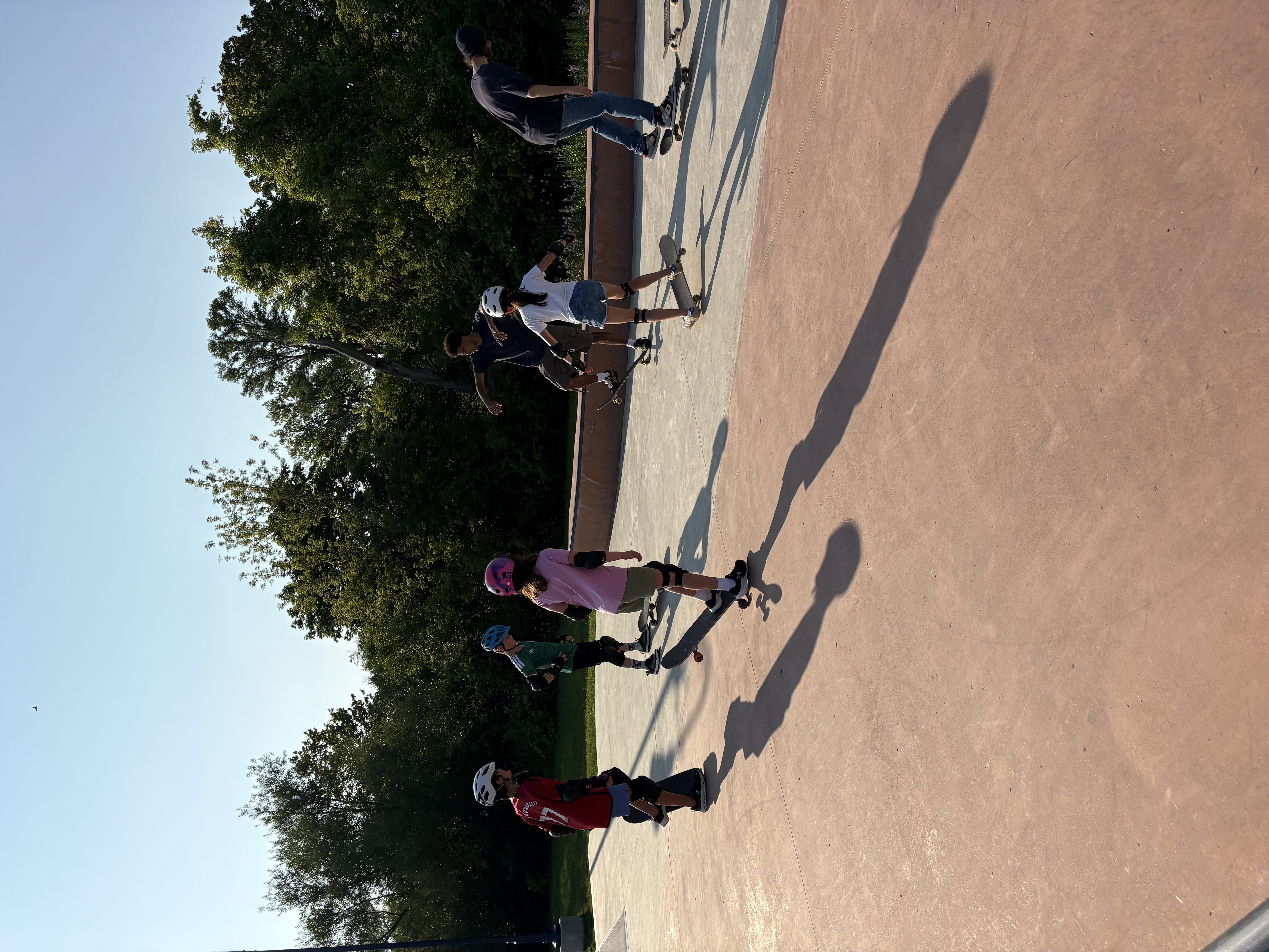 A group of young skaters with skateboards on a concrete skate plaza at sunset