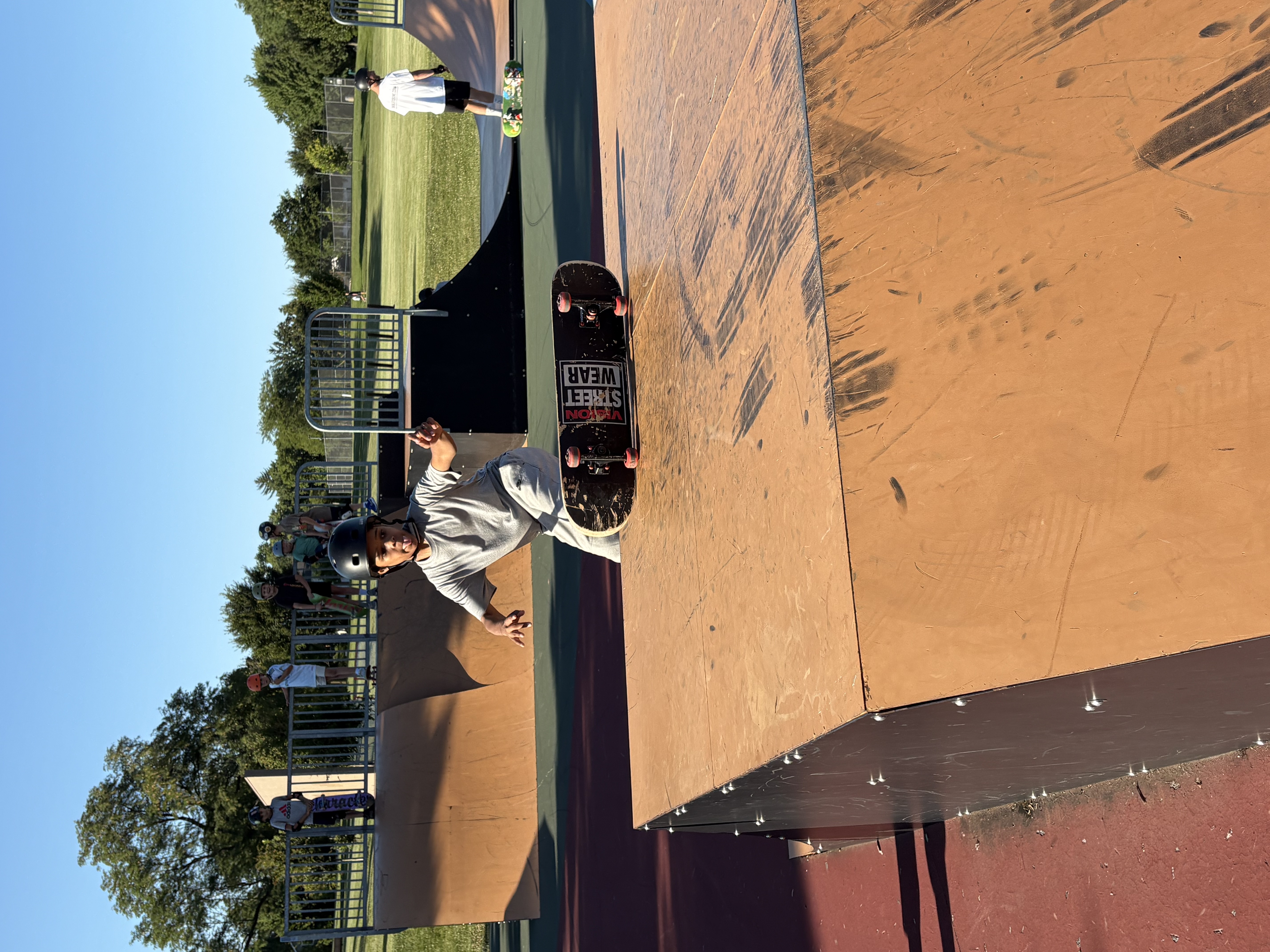 A young skater flipping a skateboard on top of a ramp platform at Newton Park's skate park