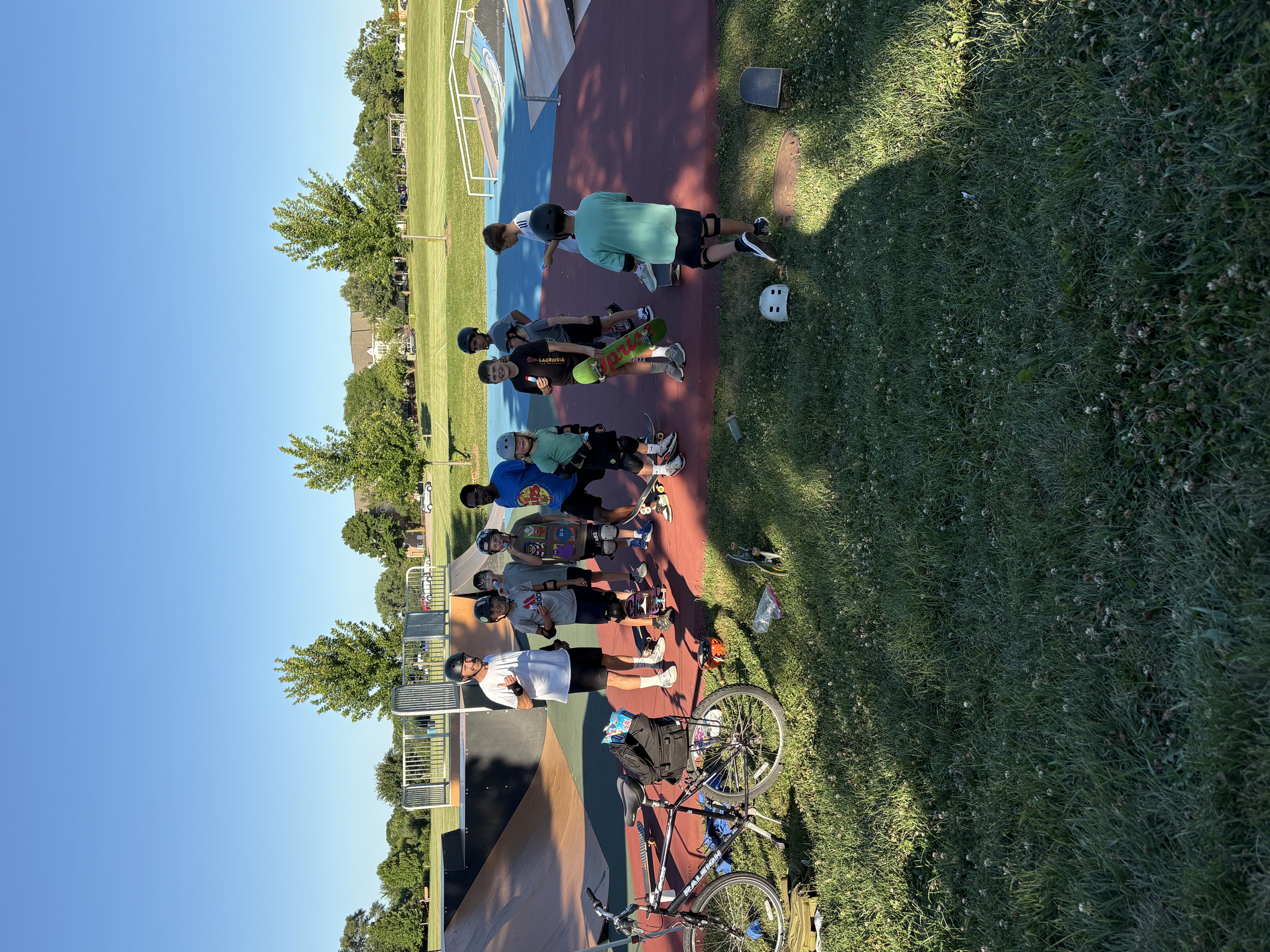A coach and a group of young skaters with skateboards standing together on the ramps at Newton Park