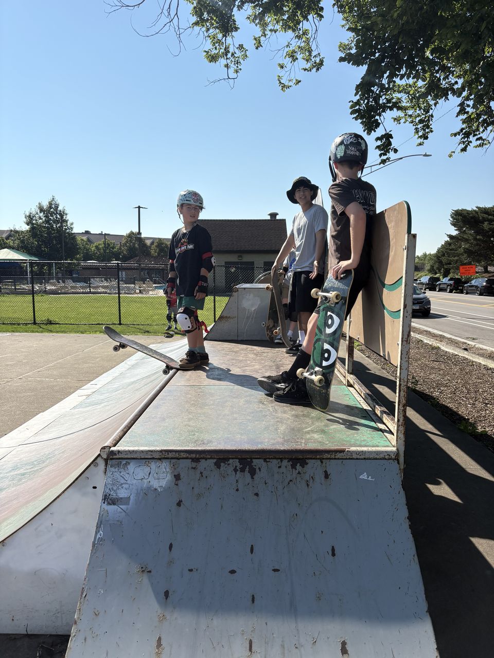 Skate Lessons Chicago students standing with their skateboards on a ramp feature at Hinkley Skate Park in Park Ridge