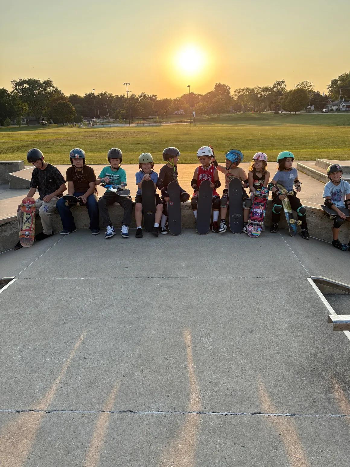 Skate Lessons Chicago students with their skateboards at Roselle Skate Park at sunset
