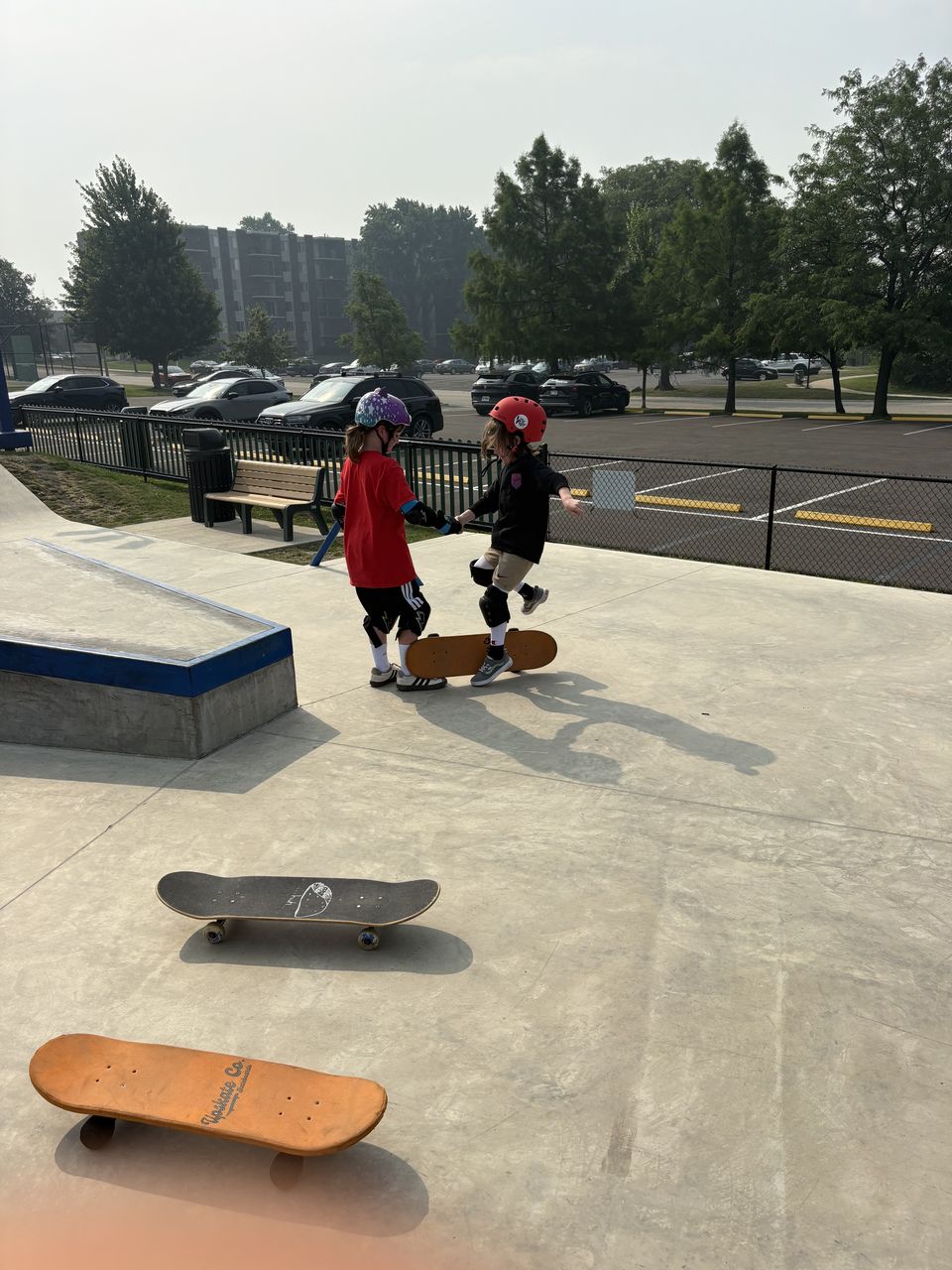 Two young skaters holding hands while learning to balance at All Wheels Park in Westmont